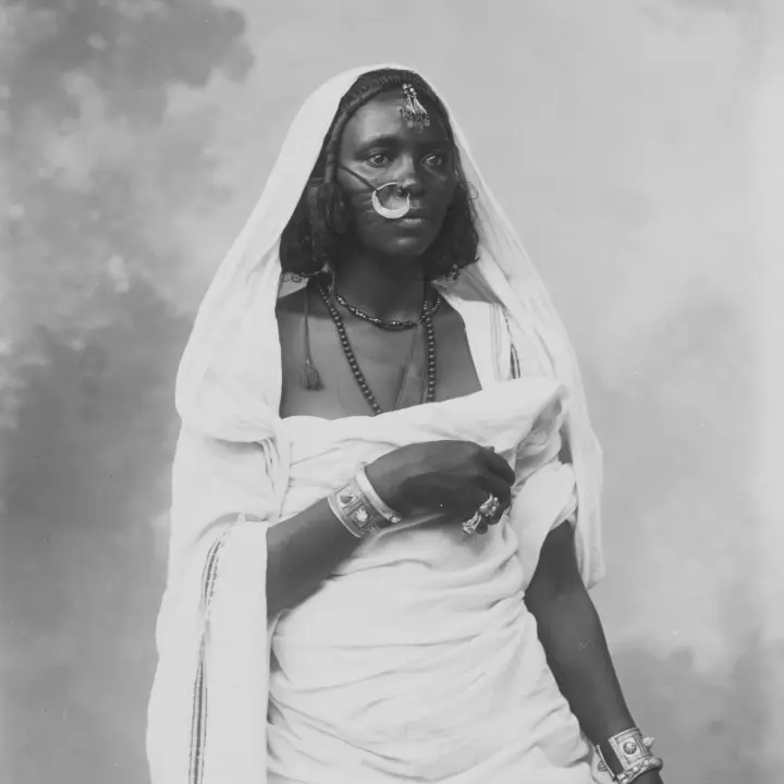 Portrait of an African Woman dressed in traditional costume, wearing decorative jewelry.